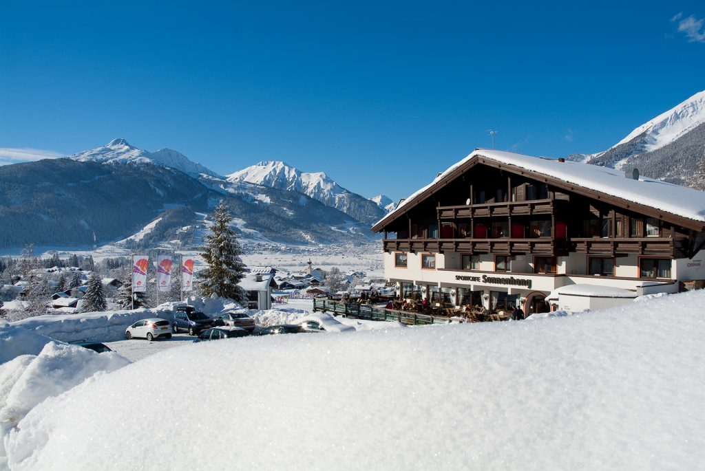 Winter in Ehrwald im DER SONNENHANG Winterlandschaft in Ehrwald. Appartementhaus im Bild, davor ein großer Schneehaufen, Schneekristalle erkennbar.
